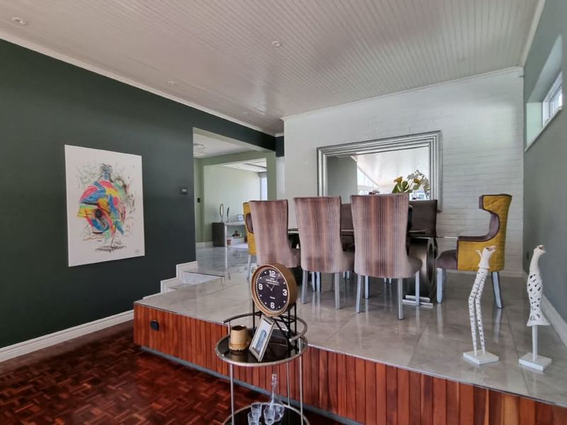 A dining area featuring a raised platform with tiled flooring, wood paneling, and a beadboard ceiling, creating a distinct and elevated dining space.