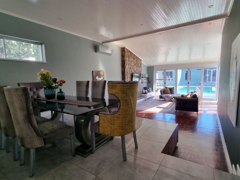 Spacious open-plan living and dining area featuring a stone fireplace, split-system air conditioning, and direct access to the outdoor pool area.