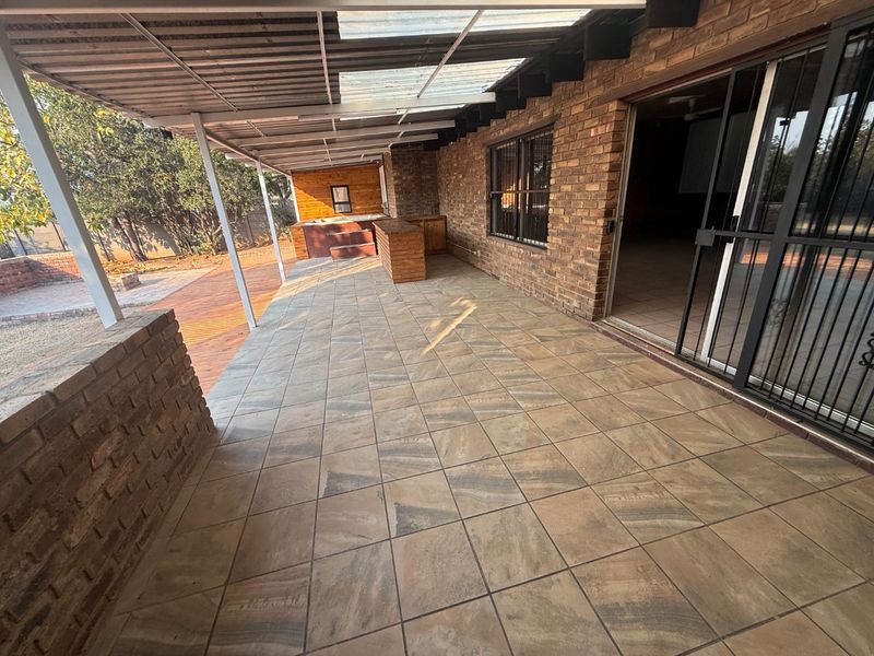 Spacious covered patio featuring tiled flooring, a built-in bar, and a built-in jacuzzi, providing an ideal space for outdoor entertaining.