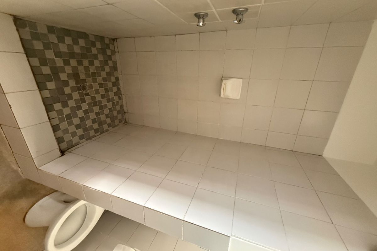 A dated bathroom featuring a tiled shower enclosure and standard toilet, requiring cosmetic updates to improve its overall condition and appeal.