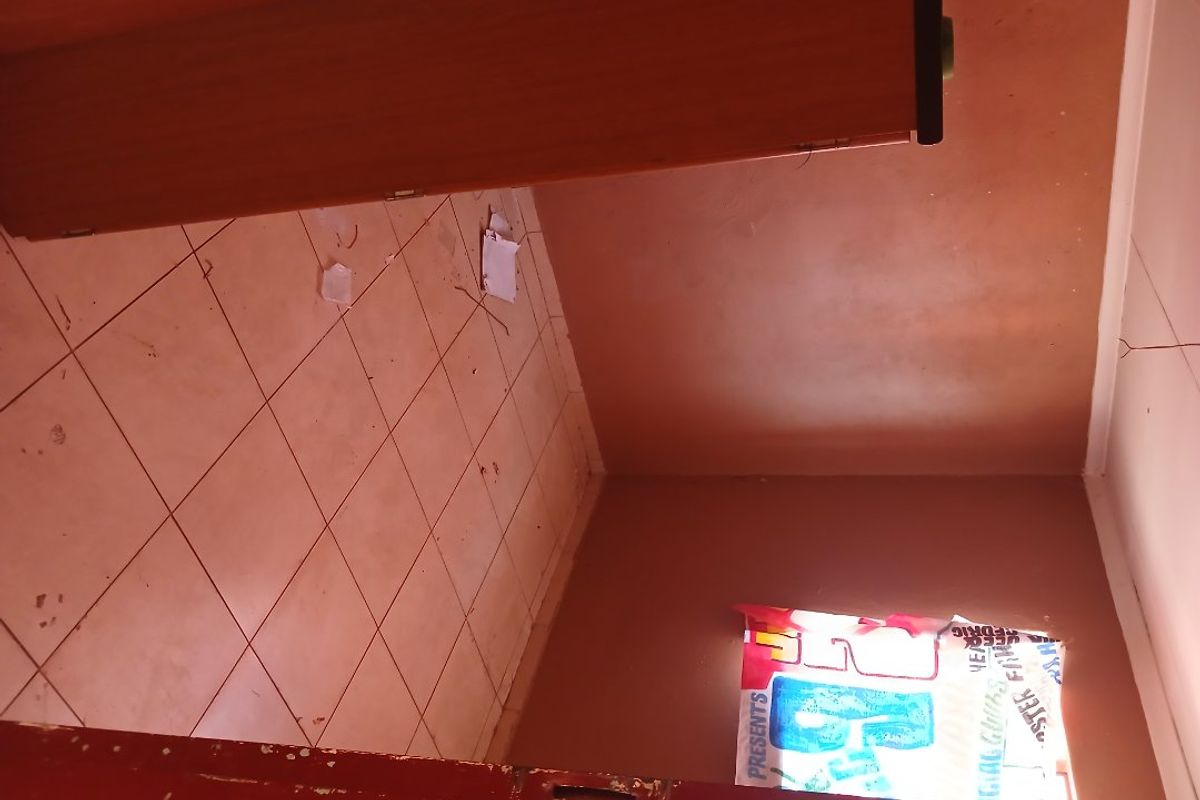An empty bedroom featuring tiled flooring and coved ceilings, currently in need of cosmetic repairs and refurbishment.