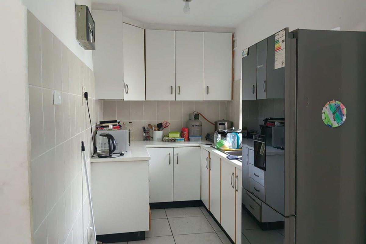 A functional kitchen featuring white built-in cabinetry, tiled backsplash, and tiled flooring, providing a practical workspace with integrated oven and sink.