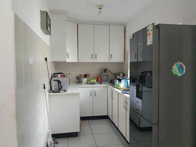 A functional kitchen featuring white built-in cabinetry, tiled backsplash, and tiled flooring, providing a practical workspace with integrated oven and sink.