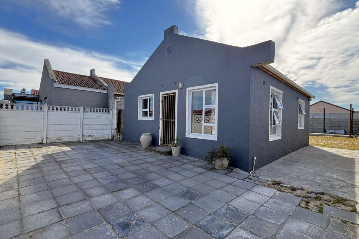 Rear view of the house featuring a paved patio area, secure entrance, and precast concrete boundary walls.