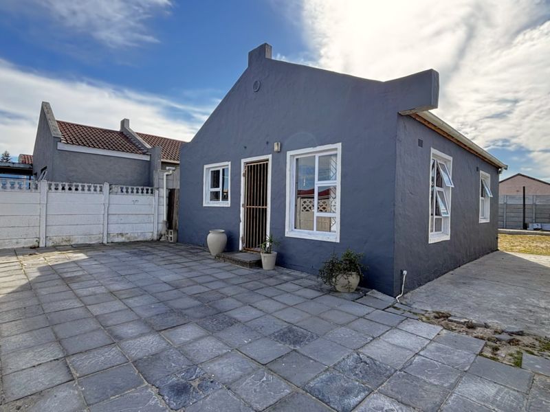 Rear view of the house featuring a paved patio area, secure entrance, and precast concrete boundary walls.