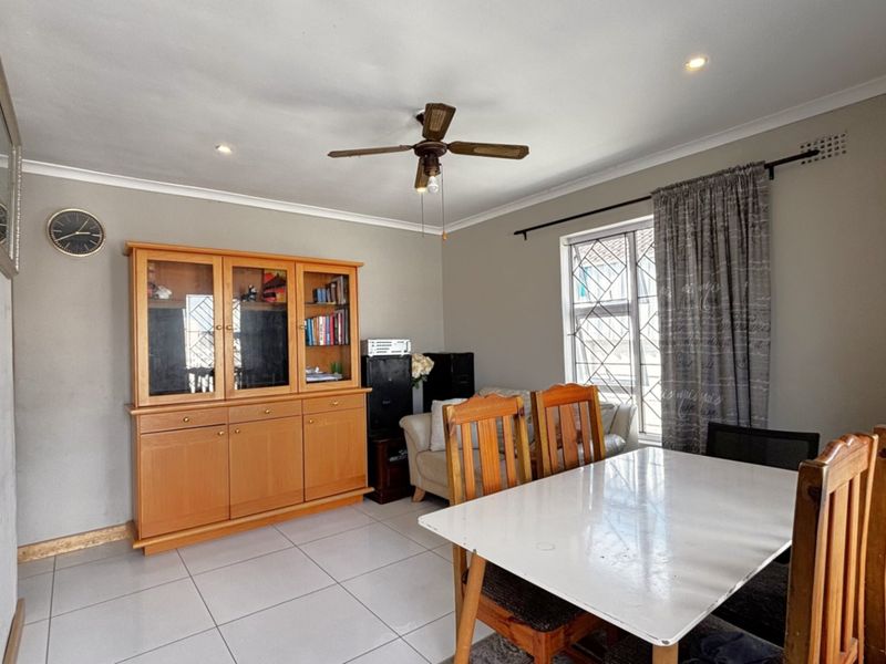 A dining area featuring tiled flooring, a ceiling fan, and recessed lighting, with security bars fitted to the window.