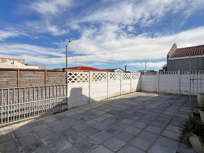 A paved rear courtyard area featuring a combination of precast concrete walling and wooden fencing, providing a private outdoor space.