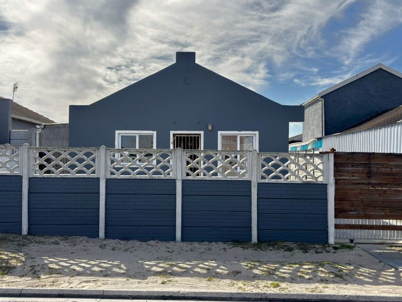 Front elevation of a detached house featuring a painted exterior, secure boundary wall with sliding gate, and modern window frames.