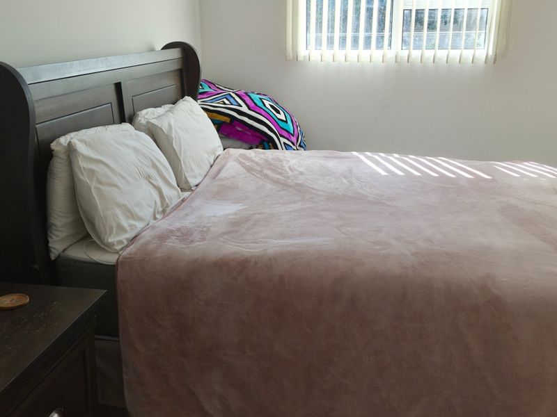 A standard bedroom featuring neutral walls and vertical window blinds, providing a functional and private sleeping space.