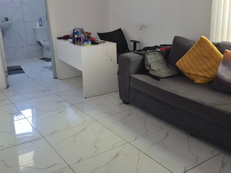 Living area featuring large format marble-look floor tiles and vertical blinds, with direct access to an adjacent bathroom.