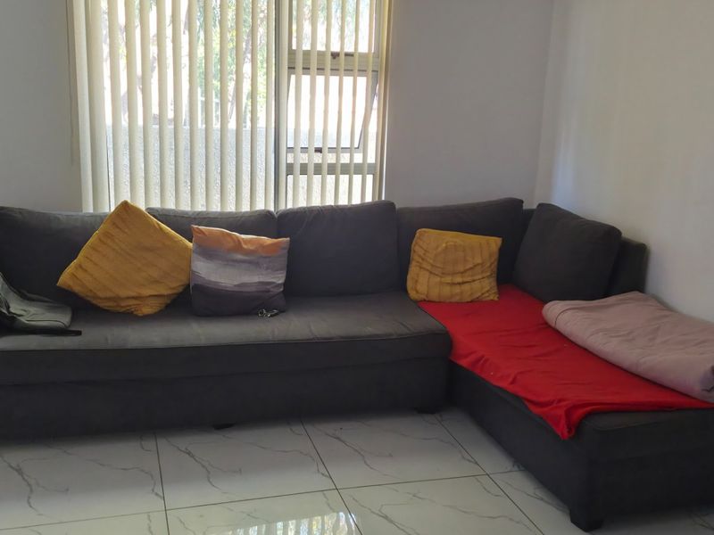 A living room featuring large format white marble-look floor tiles and vertical window blinds.