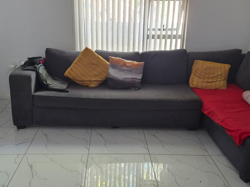 A living room featuring large marble-look floor tiles and vertical window blinds, with visible wall surface wear.