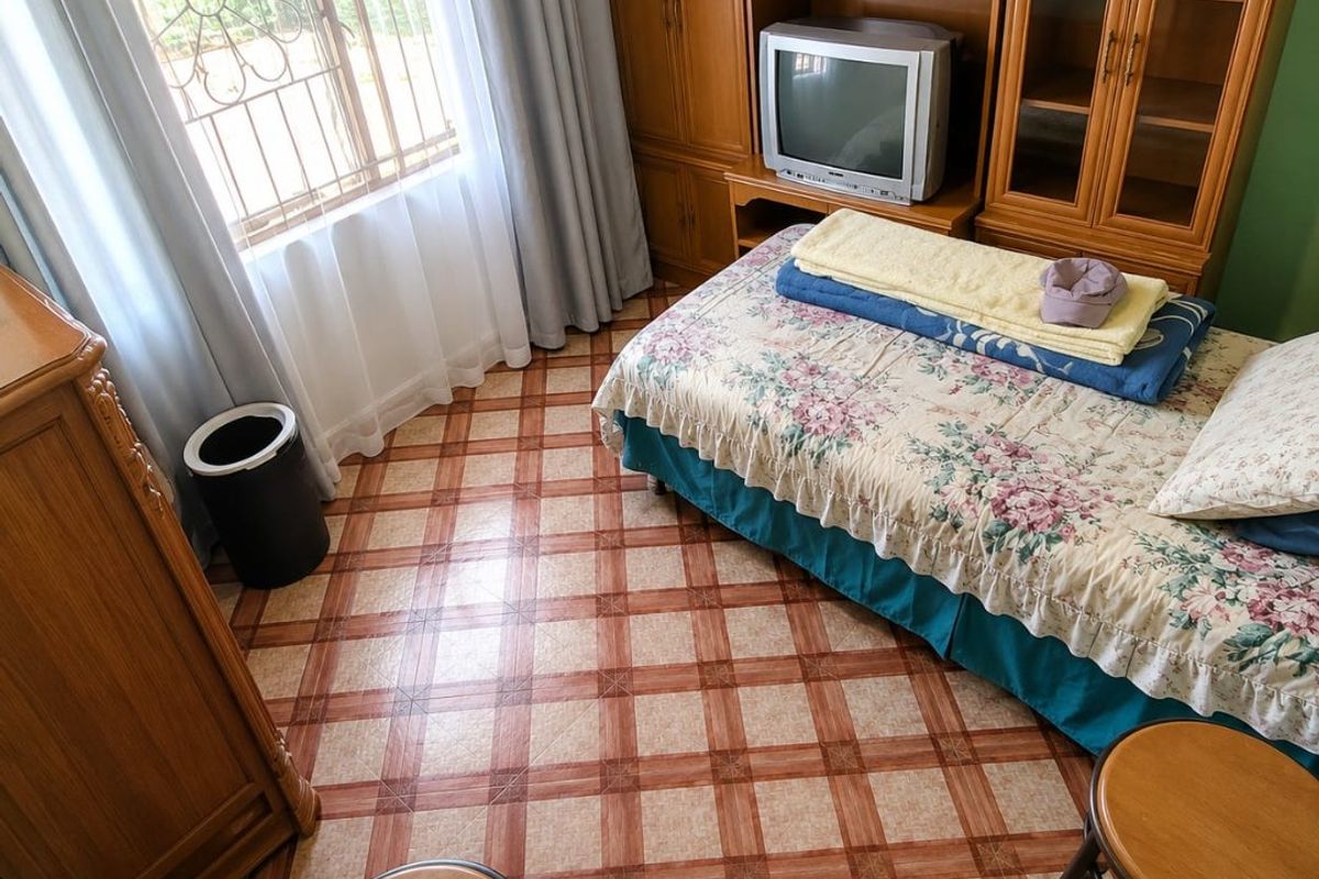 A bedroom featuring tiled flooring, security bars on the window, and built-in wooden cabinetry providing storage space.
