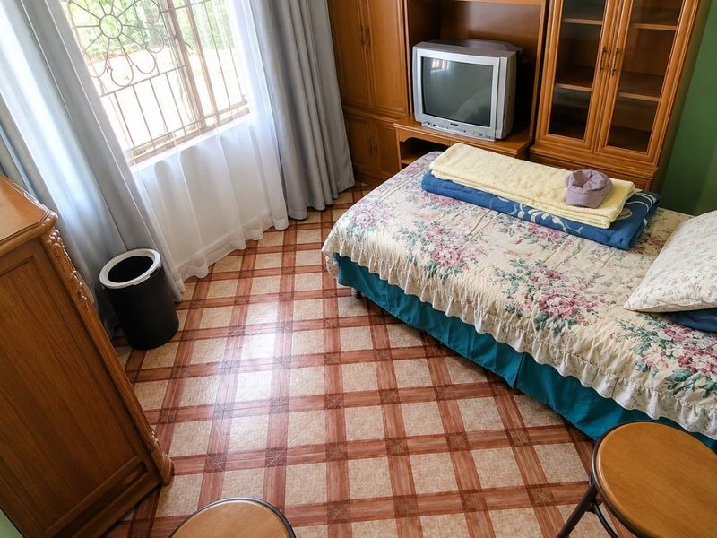 A bedroom featuring tiled flooring, security bars on the window, and built-in wooden cabinetry providing storage space.