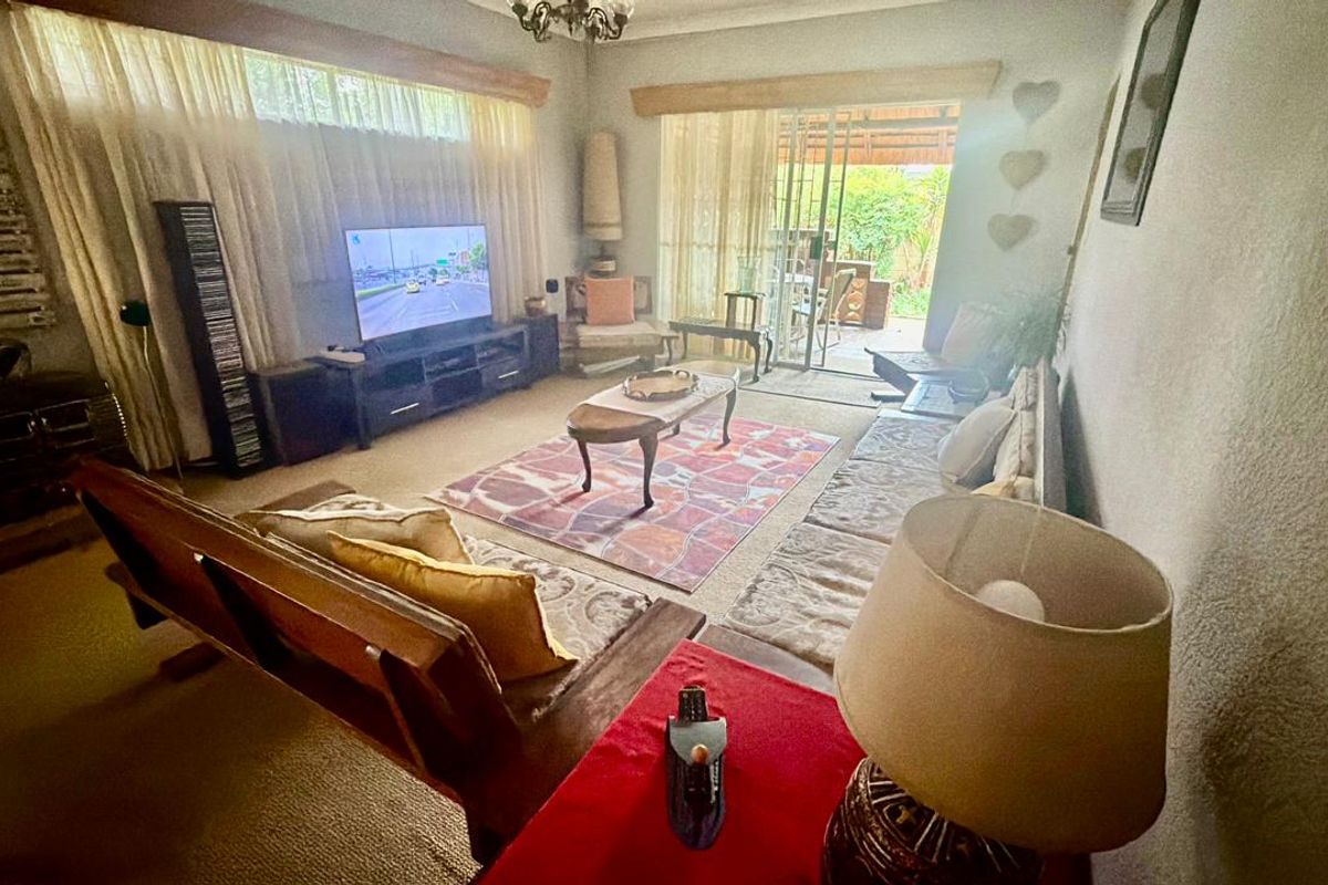A comfortable living room featuring large windows, a fireplace, and sliding glass doors that provide direct access to the outdoor patio area.