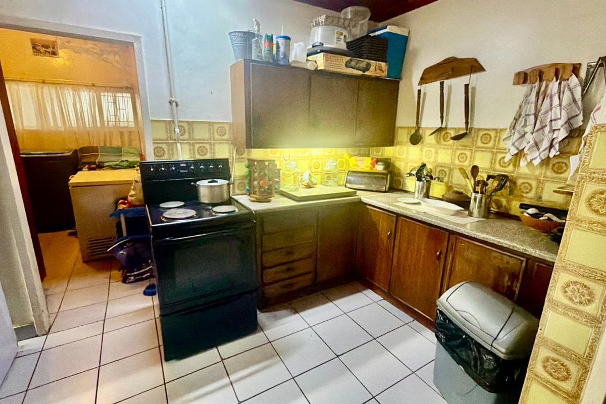 A functional kitchen featuring dated cabinetry, a tiled backsplash, and ceramic flooring, offering potential for a modern renovation to enhance the space.