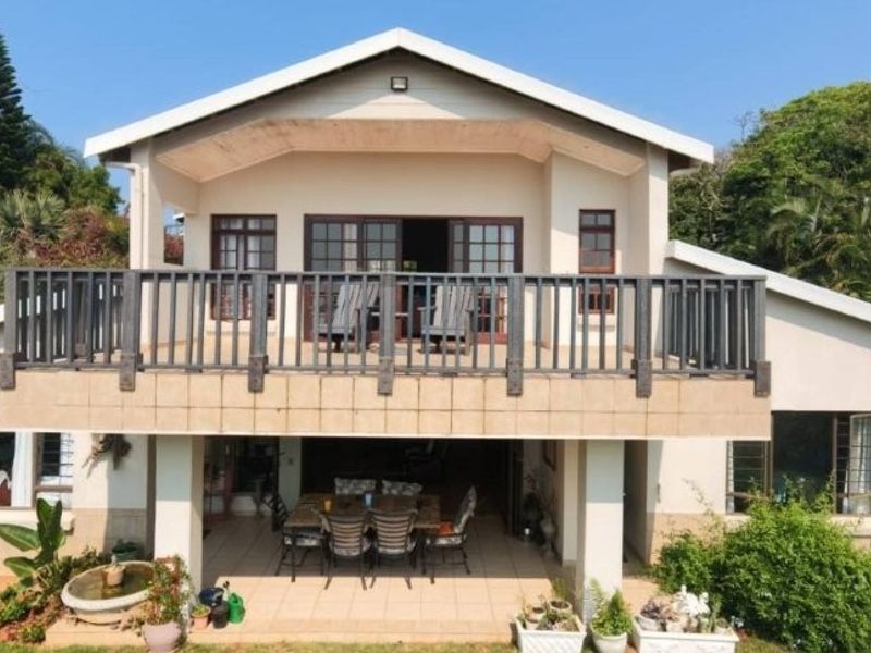 Rear elevation of a two-story house featuring a spacious covered patio on the ground level and a large balcony above with timber balustrades.