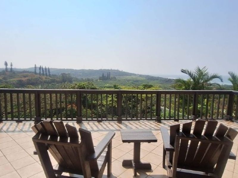 Spacious elevated balcony featuring tiled flooring and a timber balustrade, offering expansive scenic views of the surrounding landscape and coastline.