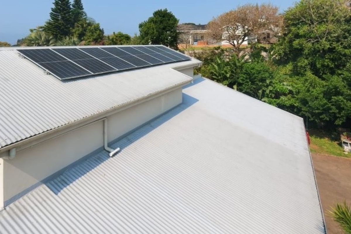 Aerial view of the property roof featuring installed solar panels, corrugated metal roofing, and integrated guttering system.