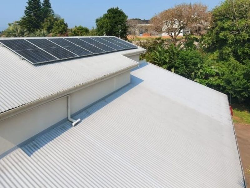 Aerial view of the property roof featuring installed solar panels, corrugated metal roofing, and integrated guttering system.