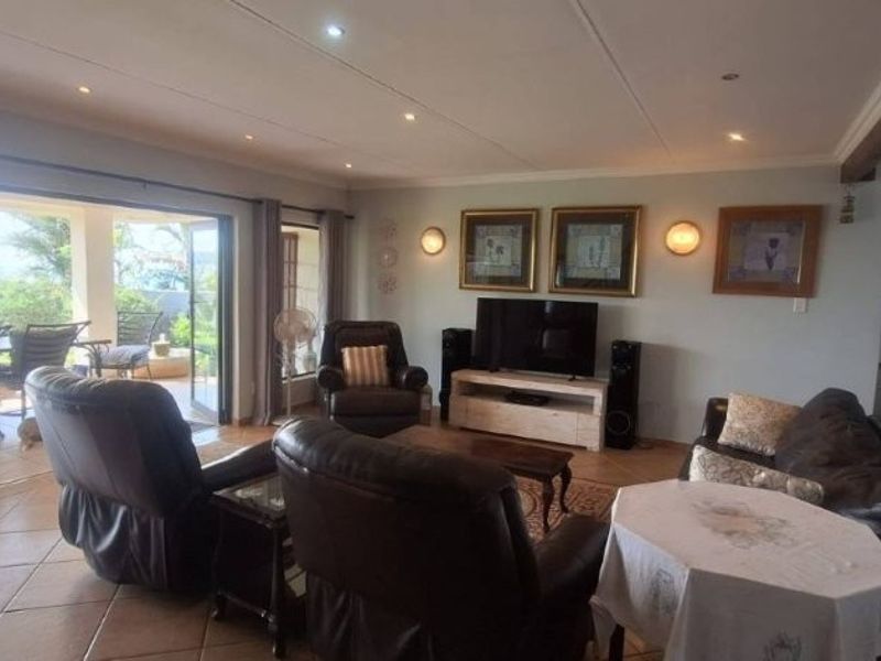 Spacious open-plan living area featuring tiled floors, recessed lighting, and large sliding doors providing seamless access to a covered outdoor patio.