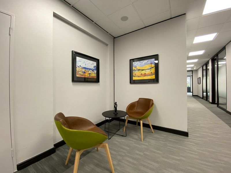 A well-maintained commercial office hallway featuring neutral walls, carpeted flooring, and recessed ceiling lighting.