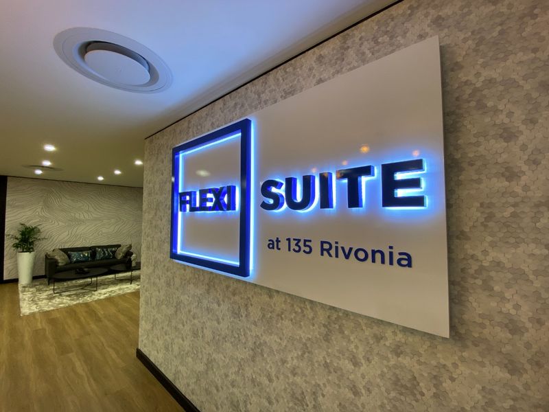 Modern commercial entrance lobby featuring professional backlit signage, contemporary textured wall finishes, and recessed ceiling lighting.