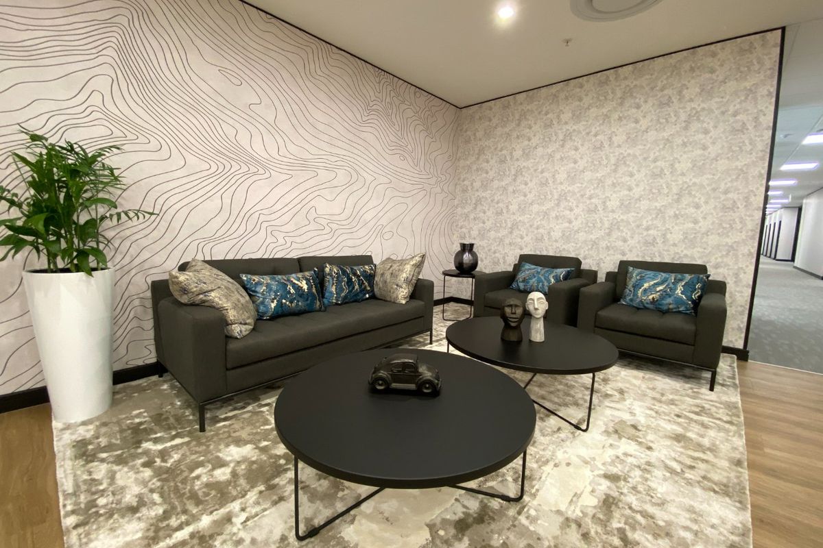 A modern, well-appointed commercial lounge area featuring contemporary patterned wallpaper, recessed ceiling lighting, and high-quality laminate flooring.