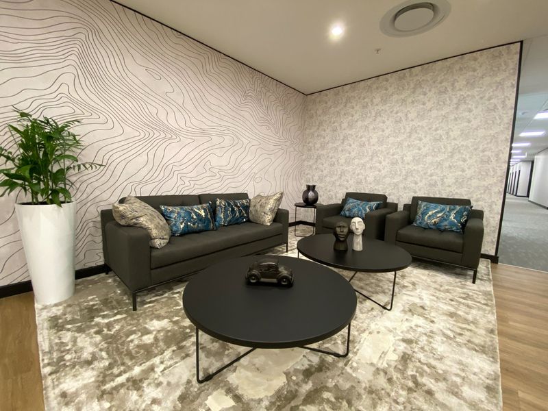 A modern, well-appointed commercial lounge area featuring contemporary patterned wallpaper, recessed ceiling lighting, and high-quality laminate flooring.