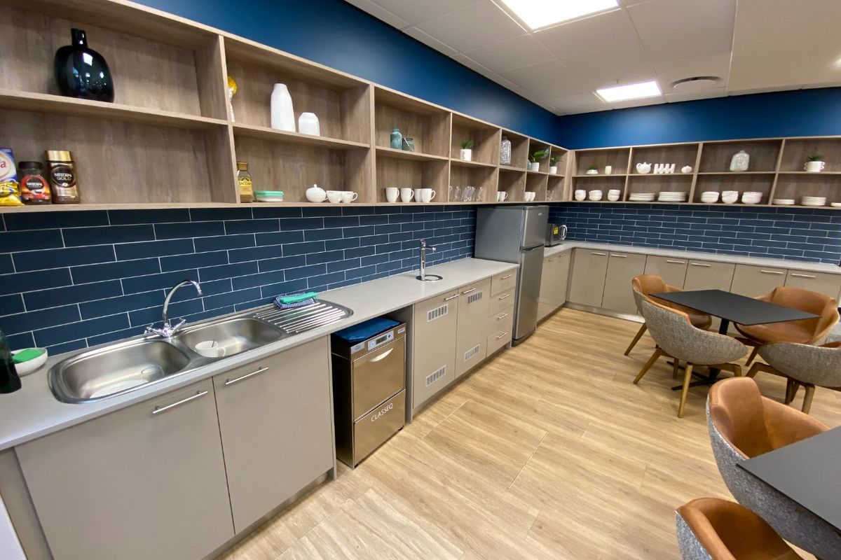 Modern commercial kitchen area featuring extensive built-in cabinetry, open shelving, subway tile backsplash, and high-quality finishes throughout.