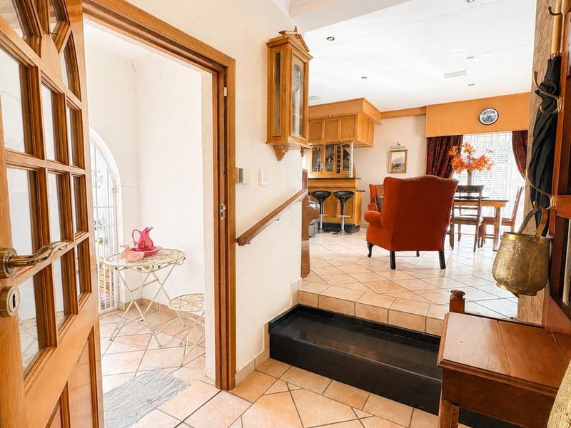 Entrance foyer featuring tiled flooring and a raised step leading into an open-plan living and dining area with traditional wooden finishes.