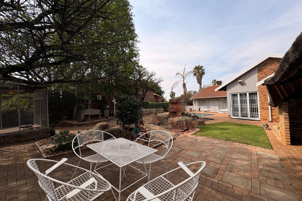 Spacious rear garden featuring a paved patio area, swimming pool, and established landscaping, providing a private outdoor entertainment space.