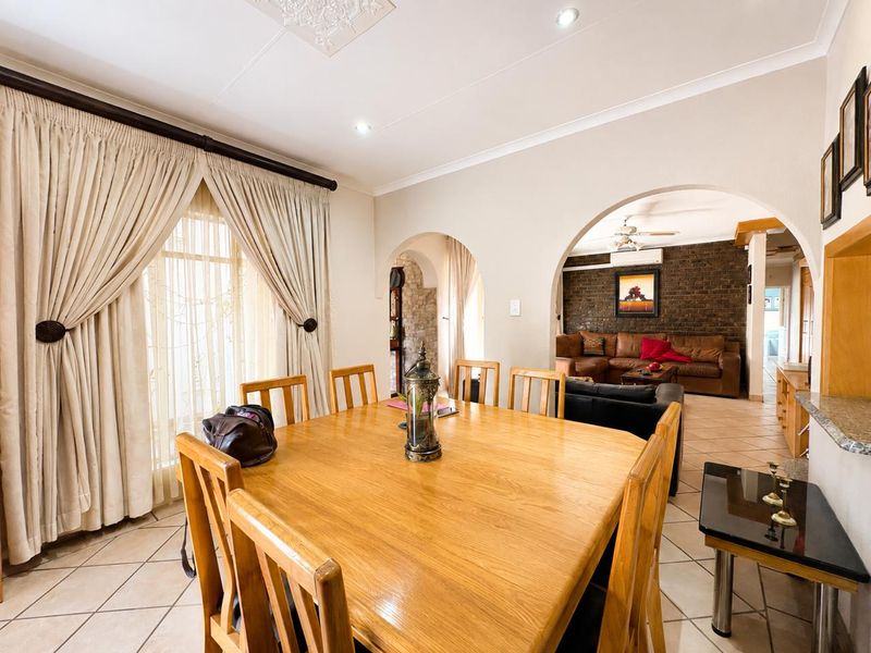 Open plan dining and living area featuring tiled floors, an exposed brick feature wall, and arched transitions between spaces.