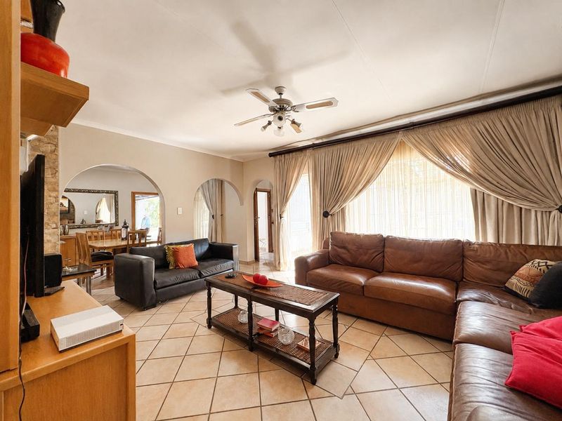 Spacious open-plan living and dining area featuring ceramic floor tiles, arched architectural details, and a ceiling fan, offering a comfortable and connected layout.
