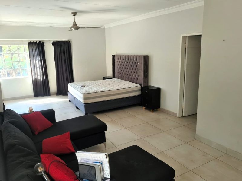 Spacious bedroom featuring neutral tiled flooring, ceiling fan, and classic cornicing, offering a versatile layout with ample natural light.