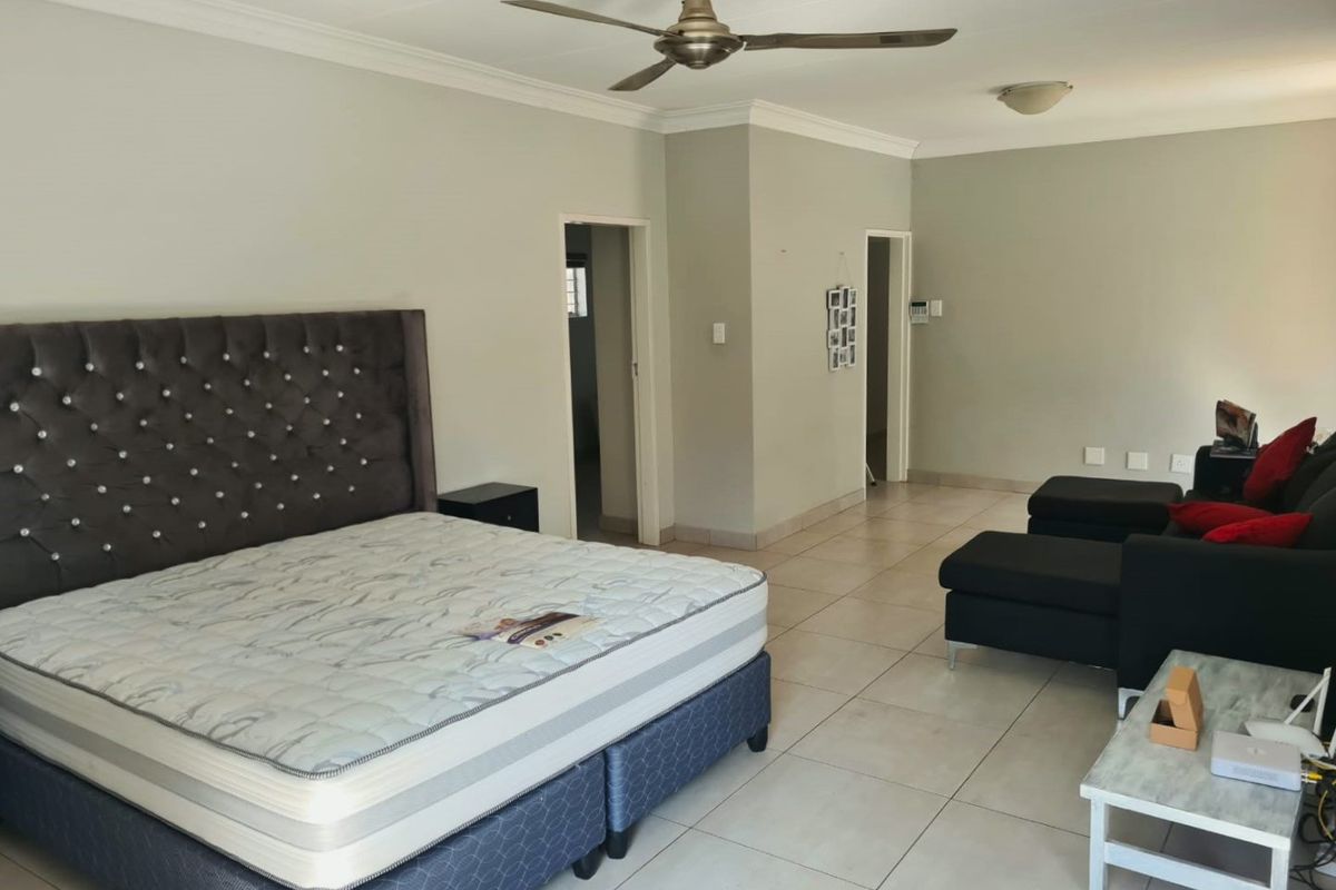 Spacious bedroom featuring neutral wall tones, tiled flooring, coved cornicing, and a ceiling fan, offering a clean and functional living space.