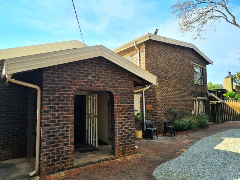 A view of the front entrance featuring a face brick facade, paved driveway, and secure gated entry.