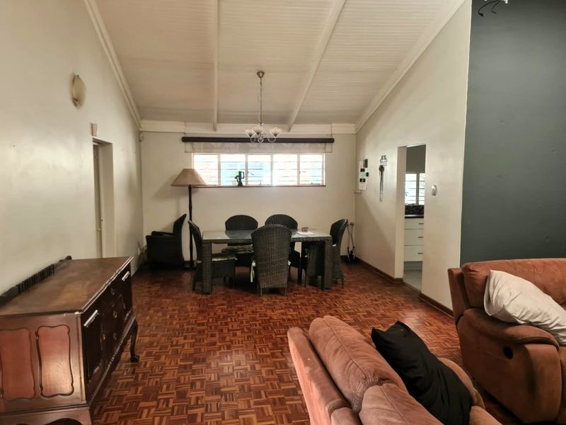 Open plan living and dining area featuring classic parquet flooring, a high vaulted ceiling with exposed beams, and direct access to the kitchen.