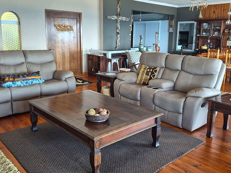 Spacious open-plan living and dining area featuring warm timber flooring, an arched window, and integrated cabinetry, offering a comfortable and functional layout.