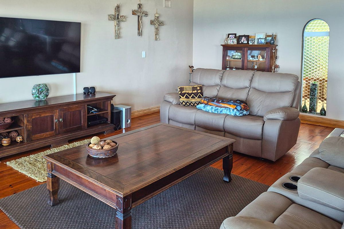 A comfortable living room featuring warm hardwood flooring and a distinctive arched window, providing a cozy and inviting atmosphere.