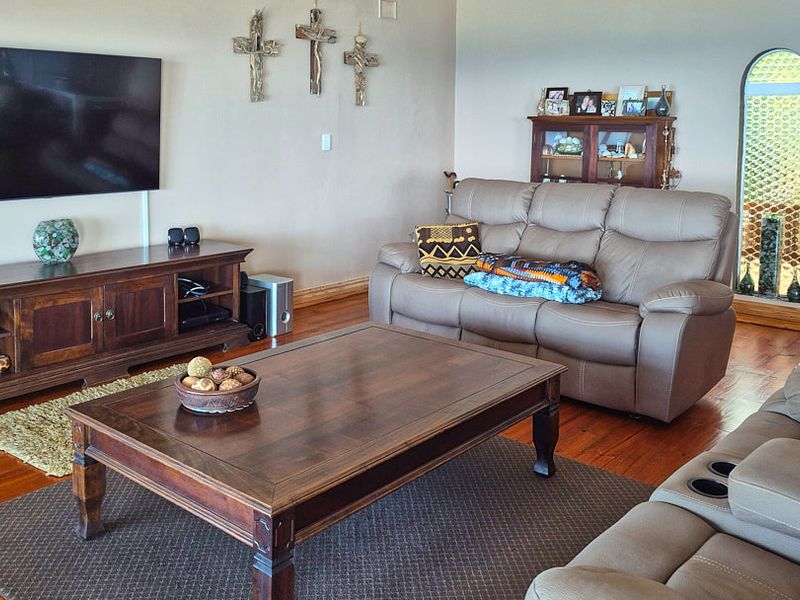 A comfortable living room featuring warm hardwood flooring and a distinctive arched window, providing a cozy and inviting atmosphere.