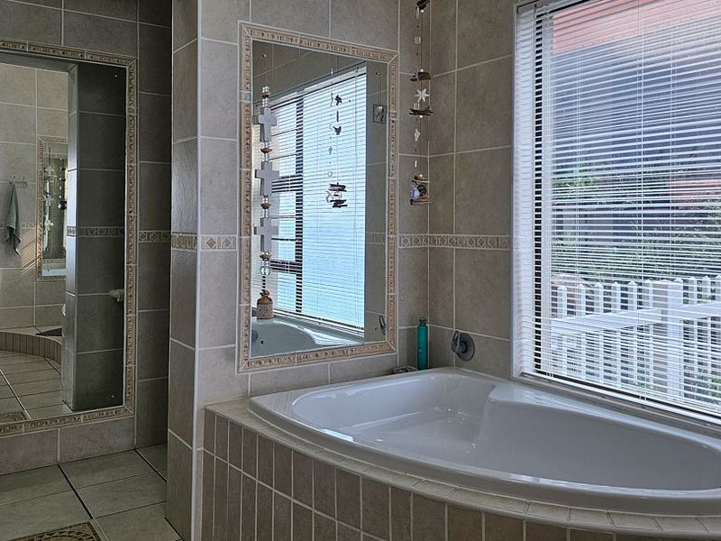 A well-maintained bathroom featuring a built-in bathtub, tiled finishes, and a large wall mirror, offering a functional and clean space.