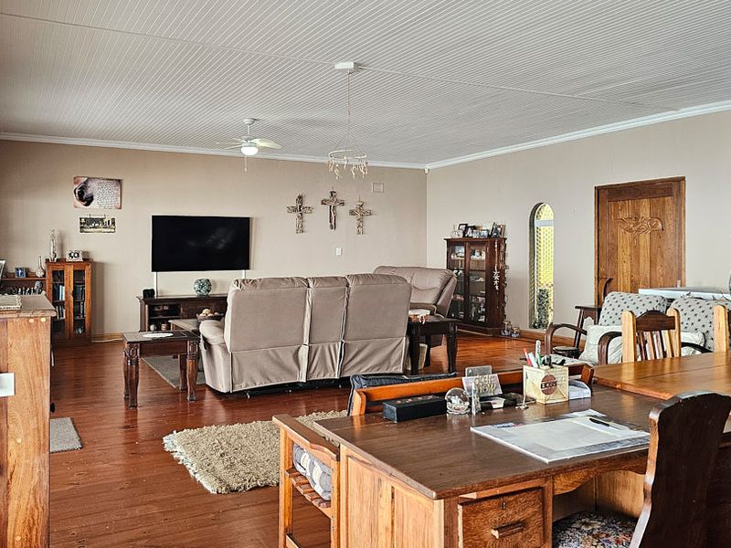 Spacious open-plan living and dining area featuring hardwood flooring, a beaded ceiling, and an arched doorway leading to adjacent spaces.