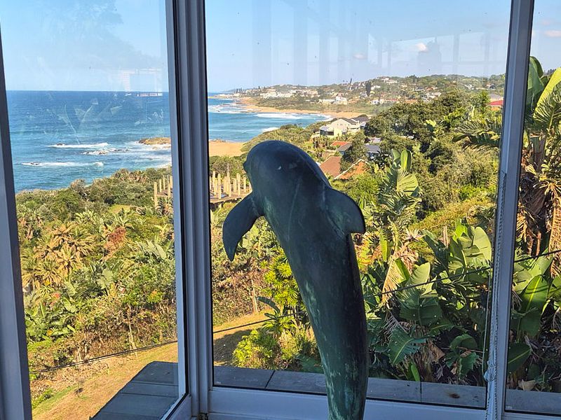 A scenic elevated view of the coastline and ocean captured through large glass windows.