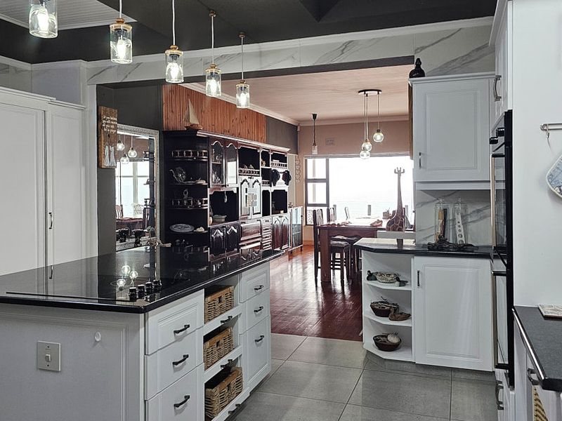 Spacious open-plan kitchen featuring a central island, modern cabinetry, stone countertops, and integrated appliances, flowing seamlessly into the dining and living areas.
