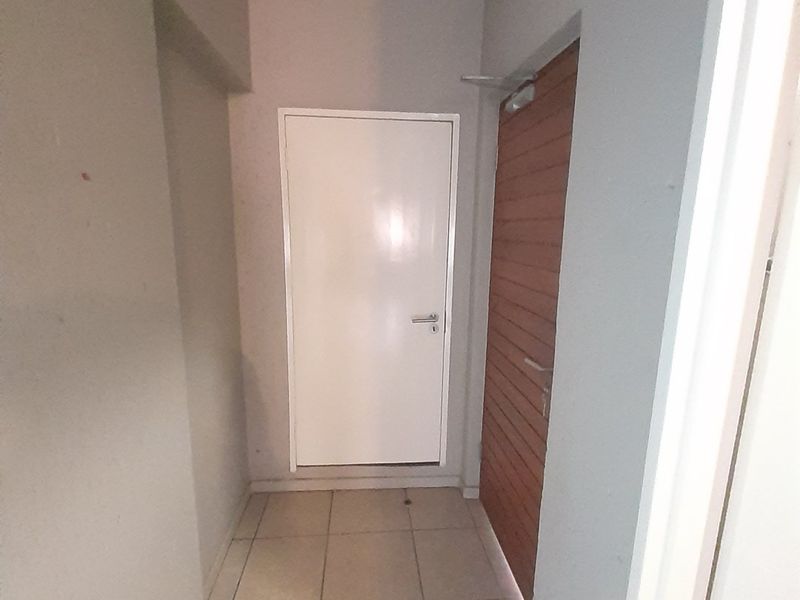 A clean and functional hallway featuring tiled flooring and two internal doors, providing access to other areas of the apartment.