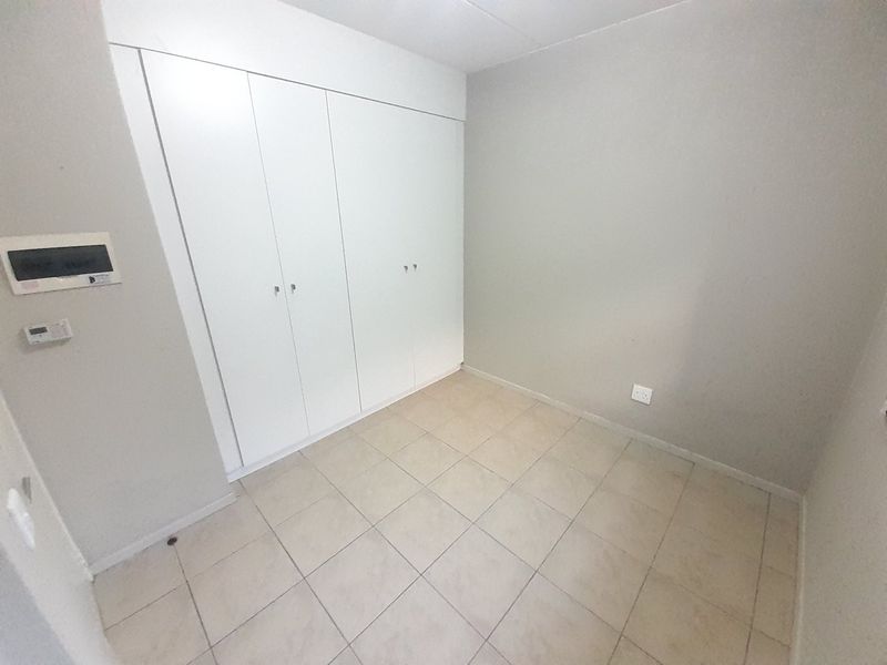 A clean, empty bedroom featuring neutral tiled flooring and ample built-in cupboard storage, ready for personalization.