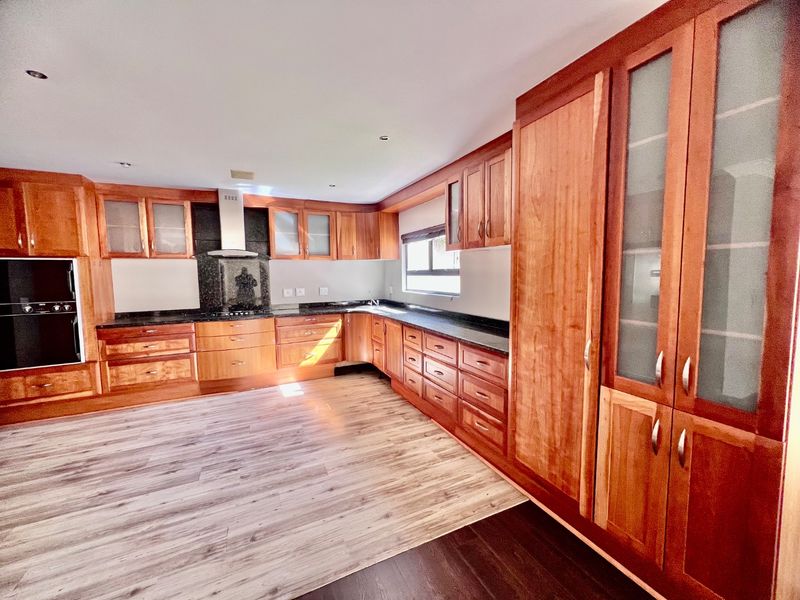 Spacious kitchen featuring extensive wooden cabinetry, granite countertops, built-in oven, and extractor fan, offering ample storage and workspace.