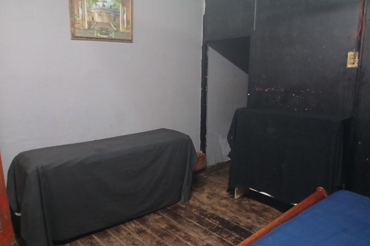 A bedroom featuring original hardwood flooring and dark wall finishes, requiring cosmetic updates and refurbishment to improve the overall condition and aesthetic appeal.