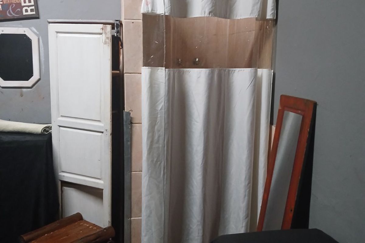 A bathroom space featuring a tiled shower enclosure with a curtain rail, requiring cosmetic updates to improve the overall finish and condition.